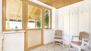 A room with a wooden ceiling, large windows, two wicker chairs, and a white radiator. - Chalet Struber - Luxury 3 Bedroom Villa In The Centre Of Zell (Zell am See)