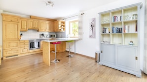 A kitchen with wooden cabinets, a white countertop, and a built-in bookshelf. - Chalet Struber - Luxury 3 Bedroom Villa In The Centre Of Zell (Zell am See)