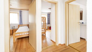 A bedroom with a wooden bed, a nightstand, and a window with curtains. - Chalet Struber - Luxury 3 Bedroom Villa In The Centre Of Zell (Zell am See)