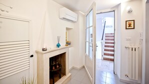 Un pasillo con chimenea, equipo de aire acondicionado, radiador y una escalera que conduce a otra habitación.