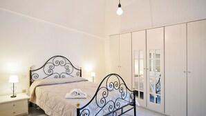 Un dormitorio con cama, mesitas de noche, armario y lámpara colgante.