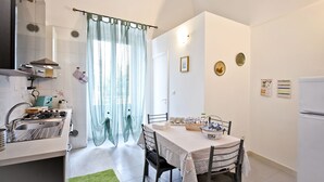 Una cocina compacta con estufa a gas, pileta y comedor con mesa y sillas.