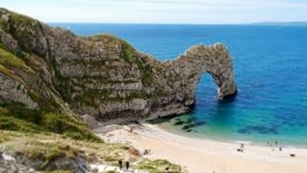 A coastal landscape with a prominent rock formation arching over the sea, a sandy beach, and a grassy cliff. - 2 Bed / 2 Bath Contemporary apartment. Close to beach, Lift access & Parking 4*  (Bournemouth)
