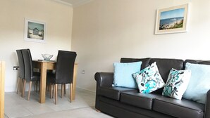 A living room with a black leather sofa, two chairs, a wooden dining table, and two framed pictures on the wall. - 2 Bed / 2 Bath Contemporary apartment. Close to beach, Lift access & Parking 4*  (Bournemouth)