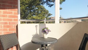 A small outdoor patio with a round table and two chairs, a potted plant, and a brick wall. - 2 Bed / 2 Bath Contemporary apartment. Close to beach, Lift access & Parking 4*  (Bournemouth)