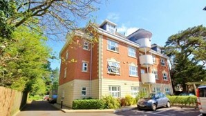 A multi-story residential building with a brick facade, multiple windows, and a cylindrical structure on the roof. - 2 Bed / 2 Bath Contemporary apartment. Close to beach, Lift access & Parking 4*  (Bournemouth)