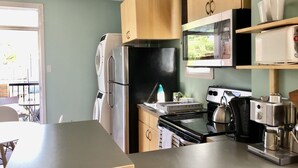 Une cuisine compacte équipée d’un réfrigérateur, d’une cuisinière, d’un four à micro-ondes et d’une machine à café.