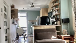 Une cuisine moderne équipée d’un four à micro-ondes, d’une cuisinière et de meubles de rangement en bois. On y trouve également un coin repas avec une chaise et une petite table.