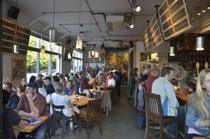 A busy restaurant with tables and chairs, a bar area, and a mural on the wall.
