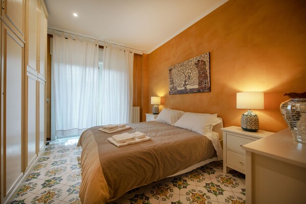 A hotel room with a bed, nightstands, a lamp, and a painting on the wall. - (Napoli)