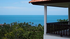 Un balcón con vista al océano y palmeras.