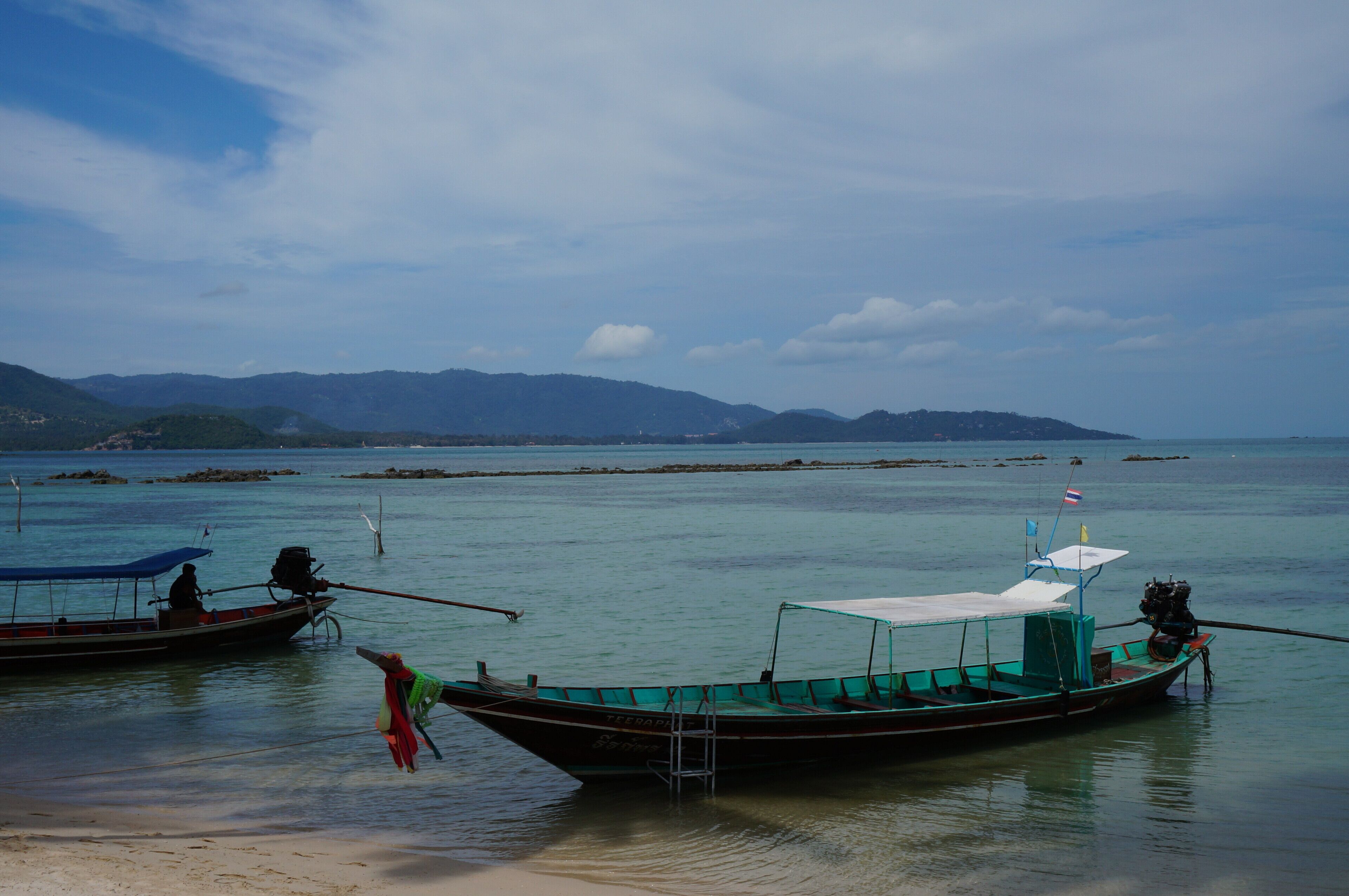 Una playa tranquila con barcos fondeados cerca de la orilla.