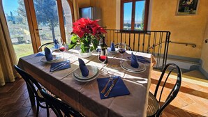 A dining area with a table set for two, a potted plant, and a view of the outdoors.