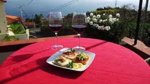 A table with a red tablecloth, two wine glasses, and a plate of food. - Typical Madeiran House in Calheta, Madeira (Estreito da Calheta)