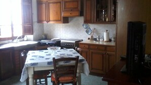 A kitchen with wooden cabinets, a stove, and a dining table with chairs. - Rustic first hill sea view in Versilia (Pietrasanta)