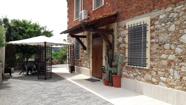 A courtyard with a covered seating area, potted plants, and a stone wall. - Rustic first hill sea view in Versilia (Pietrasanta)