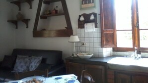 A cozy kitchen with a wooden ladder shelf, a tiled backsplash, and a window with a view. - Rustic first hill sea view in Versilia (Pietrasanta)