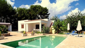 A swimming pool with a stone deck, a covered patio area, and lounge chairs. - House with pool 200 meters from the beach (S'Argamassa)