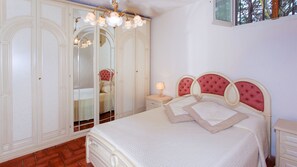 Un dormitorio con cama, mesita de noche, espejo y armario.