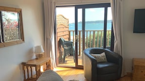 Una sala de estar acogedora con un sofá de cuero, una mesa de centro de madera y vista al mar a través de un ventanal corredero.