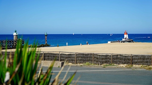 Paisaje costero con faros y una playa arenosa.
