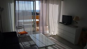 Una sala de estar moderna con una mesa de vidrio, una silla, un televisor y una lámpara.
