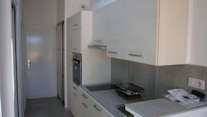 Una cocina con gabinetes blancos, un refrigerador de acero inoxidable y un fregadero.