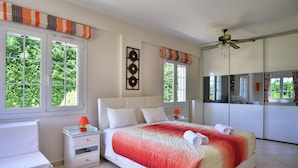 Een slaapkamer met een bed, nachtkastjes, een stoel en een plafondventilator.