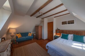 Cozy attic retreat with a comfortable bed, sofa, and wooden wardrobe.