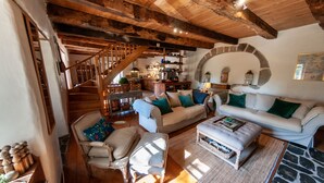 Un salón acogedor con una escalera de madera, un conjunto de sofás y una chimenea de piedra.