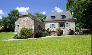 Traditional stone house with a central entrance and well-maintained lawn.
