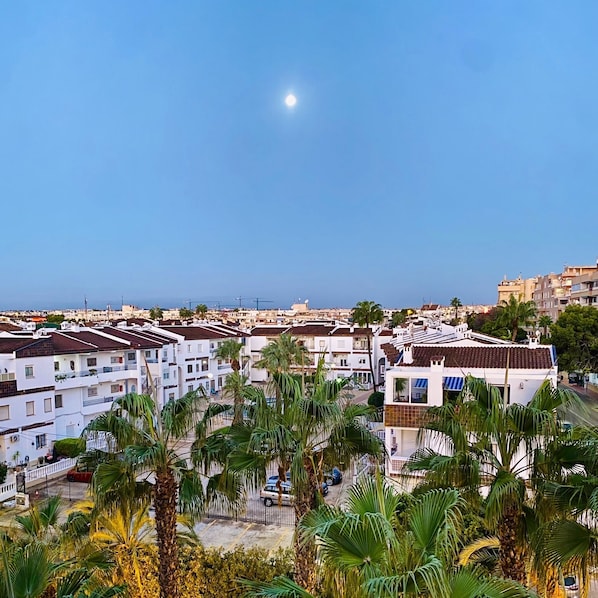 Zona residencial costera con edificios blancos, palmeras y cielo despejado.