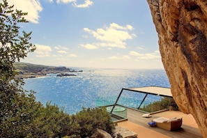 Une terrasse située au bord d’une falaise, dotée d’une balustrade en verre, d’où l’on peut admirer la mer.