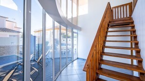 A modern interior with a wooden staircase, large glass windows, and a view of outdoor furniture. - Full private villa - 300sqm Hammam Jacuzzi Heated Pool Billiard BBQ - Ideal & quiet location (Albufeira)