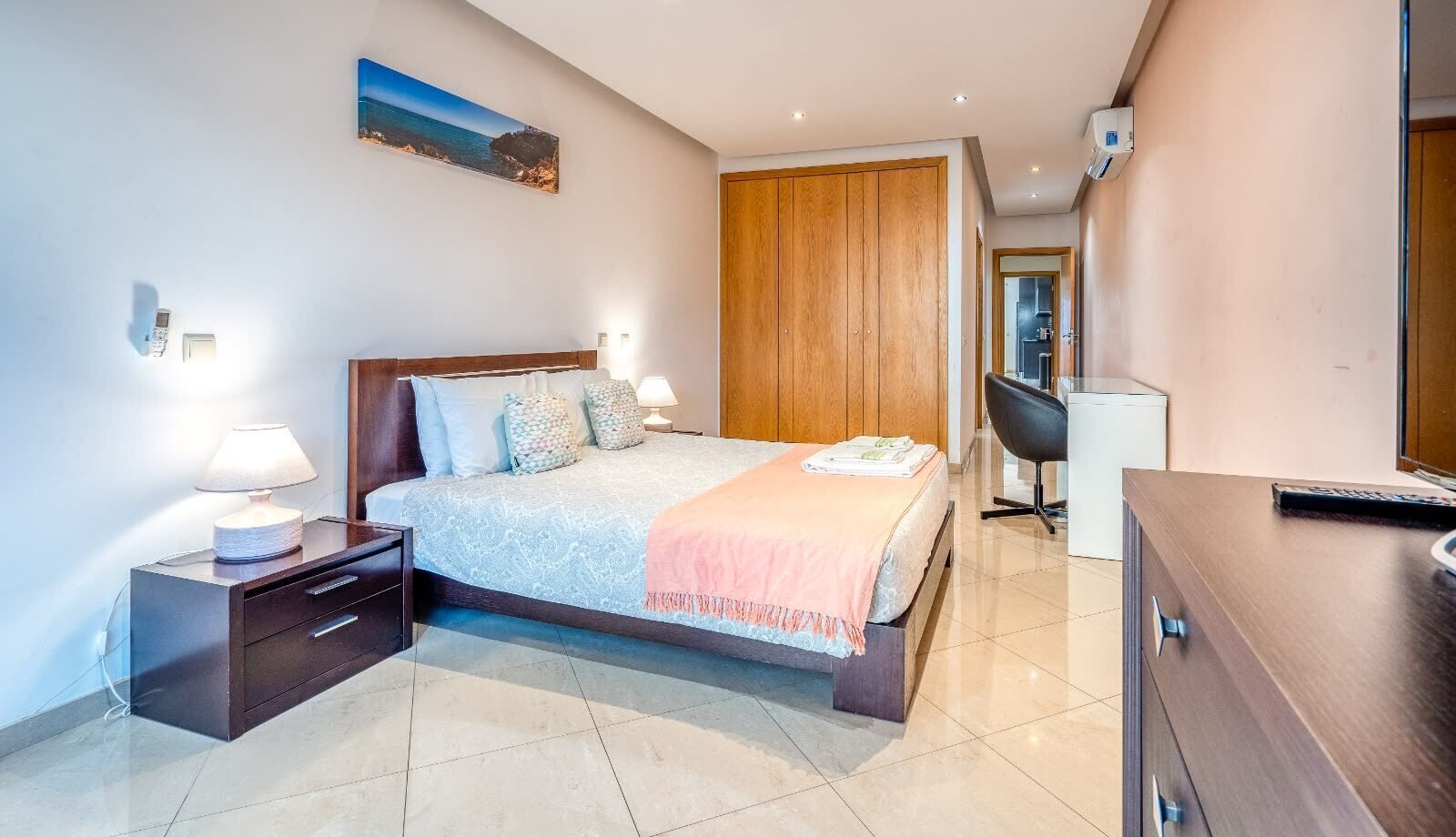 Une chambre à coucher moderne avec un lit, des tables de chevet, un bureau et une armoire.