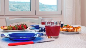 A table set with plates of food, glasses of red beverage, and a blue plate.