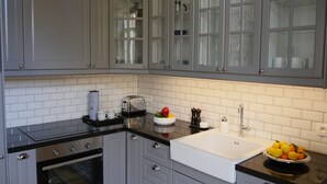 A modern kitchen with grey cabinets, a black countertop, a white sink, and a fruit bowl.