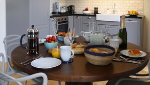 A modern kitchen with grey cabinets, a stainless steel oven, and a dining table set with breakfast items.