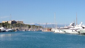 A marina with numerous yachts docked, a castle in the background, and a clear sky.