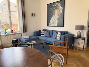 Moderni olohuone, jossa on sininen sohva, puinen sohvapöytä ja ruokailutila.
