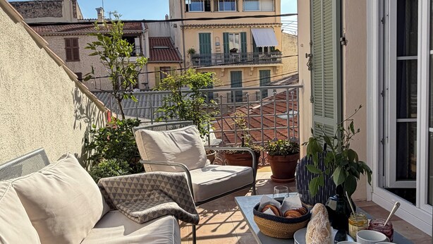 A balcony with outdoor furniture, potted plants, and a table with food items.