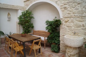 Un patio con tavolo e sedie in legno, un lavello in pietra e piante in vaso.