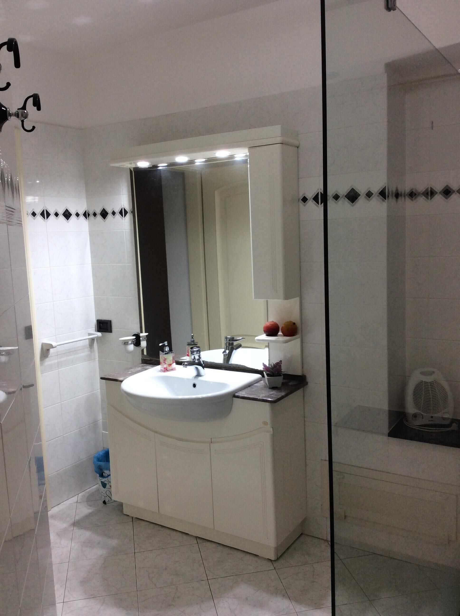 Une salle de bain avec un lavabo blanc, un miroir et un espace douche.