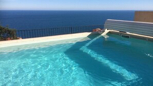 Piscina azul límpida com vista para o oceano.