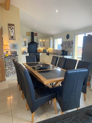 A modern kitchen with white cabinets, a black stove, and a dining area with a glass-top table and black chairs.