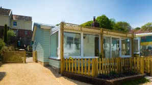 A small, single-story house with a fenced garden area and a clear sky. - Homestead, Lyme Regis is a cosy riverside cabin, 10 mins walk from the beach (Lyme Regis)