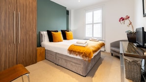 Ein modernes Schlafzimmer mit Bett, Kleiderschrank und Fernseher auf einem Schrank.