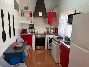Compact kitchen with a stove, oven, dishwasher, sink, and microwave, plus a dining table and chairs.