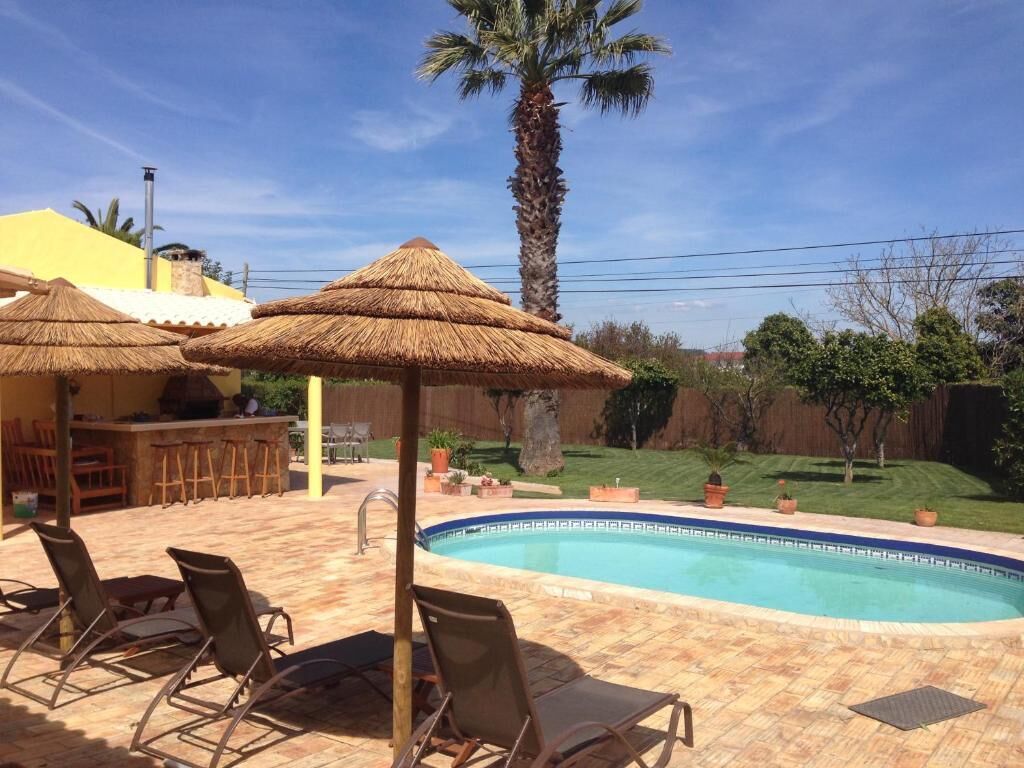A backyard with a swimming pool, lounge chairs, and a barbecue area.