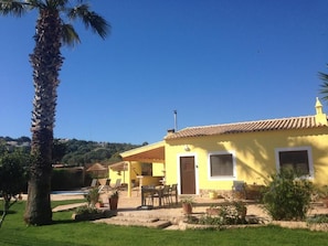 Relax in a serene garden setting with an entrance, outdoor seating, and a pool nearby.